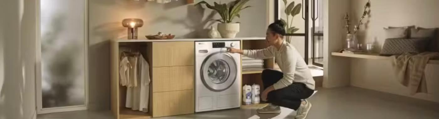 person crouching in front of a modern washer and dryer